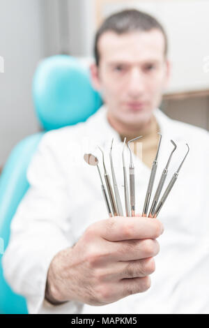 Dentiste holding ses outils dans sa main tendue, close-up. Arrière-plan flou Banque D'Images