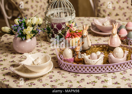 Composition décorative de Pâques sur un arrière-plan d'époque. Au printemps. Un pot de fleurs avec des fleurs, un muscari lapins en porcelaine, des œufs dans le foin. Concept de Pâques Banque D'Images