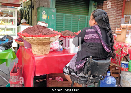 Femme assise à son stand extérieur ingrédients de cuisine vente à Oaxaca, au Mexique. Banque D'Images
