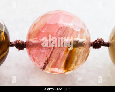 La prise de vue macro des eaux minérales naturelles rock specimen - cordon de pierres de quartz rose sur fond de marbre blanc Banque D'Images