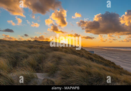 Coucher de soleil dans les dunes de sable d'Ostende, ville avec une vue sur la mer du Nord et de la plage avec la silhouette du phare en arrière-plan, la Belgique. Banque D'Images