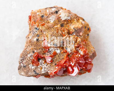 La prise de vue macro des eaux minérales naturelles rock specimen - cristaux rugueux de la Vanadinite sur de la pierre sur fond de marbre blanc du Maroc Banque D'Images