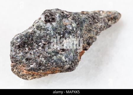 La prise de vue macro des eaux minérales naturelles rock specimen - brut de la syénite à néphéline biotite pierre sur fond de marbre blanc Banque D'Images