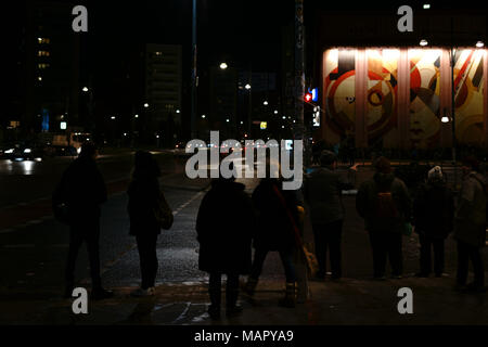 Berlin, Allemagne - Décembre 05, 2017 : la nuit des silhouettes de personnes sur place Alexander sous la pluie avec une peinture murale abstraite dans l'arrière-plan sur la D Banque D'Images