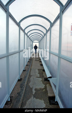 Homme debout à la fin d'un long tunnel abri bus Banque D'Images