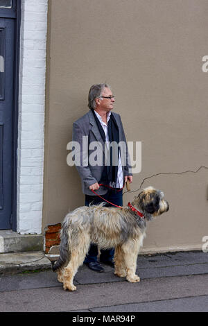 Dapper homme en manteau et une écharpe avec un chien Banque D'Images