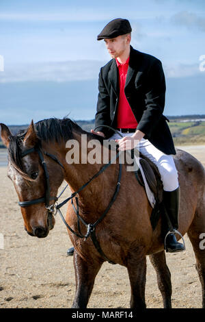 Beau mâle Horse Rider à cheval, portant chapeau plat, un pantalon blanc et des bottes noires sur la plage Banque D'Images