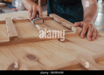 Mains d'artisan le sablage d'un morceau de bois dans l'atelier Banque D'Images