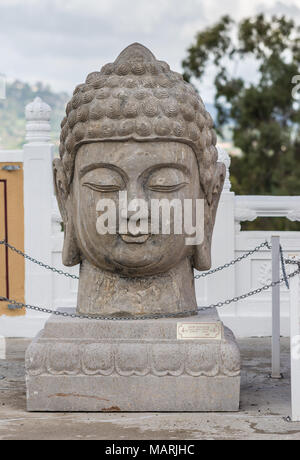 Hacienda Heights, Californie, USA - Le 23 mars 2018 : La tête de Bouddha statue en pierre à l'entrée de Hsi Lai Temple Bouddhiste sous de lourdes clo blanc Banque D'Images