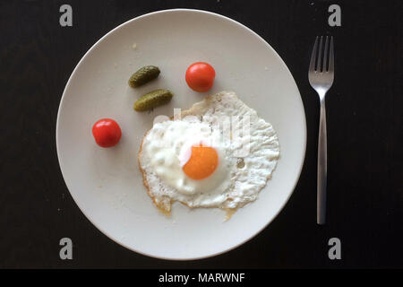 Œuf frit servi avec des tomates cerises et des concombres dans la plaque sur la table. Banque D'Images