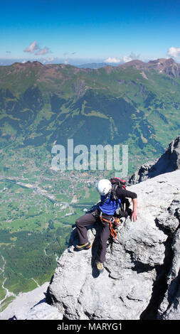 Homme d'alpiniste sur une étroite crête roche exposée sur son chemin jusqu'à la célèbre montagne de l'Eiger dans les Alpes Suisses près de Grindelwald Banque D'Images