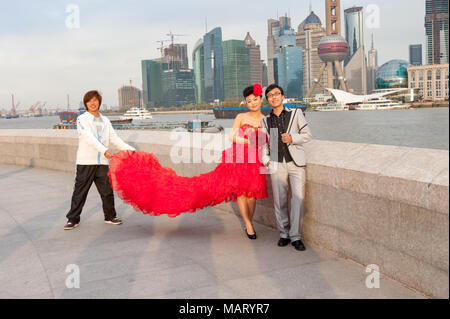 Jeune couple de jeunes mariés ayant des photos prises sur le Bund à l'encontre de la ville, Shanghai, Chine Banque D'Images