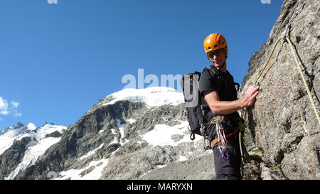 Guide sur un rebord rocheux escarpés et exposés sur son chemin à un haut sommet alpin avec un client Banque D'Images