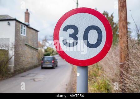 La limite de vitesse de 30 mi/h signe sur route qui traverse un pays village road,UK, Dorset Banque D'Images
