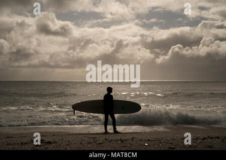 Falmouths Plage de Gyllyngvase, Cornwall, UK. 4 avril, 2018. Surfeur en contre-jour s'apprête à entrer dans l'eau à Falmouths Plage de Gyllyngvase, Cornwall Crédit : Mick Buston/Alamy Live News Banque D'Images