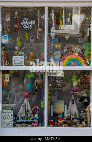 Un mélange éclectique de jouets et divers articles intéressants dans la fenêtre d'un petit chalet sur la côte de Cornouailles. Old Curiosity Shop Window display Banque D'Images