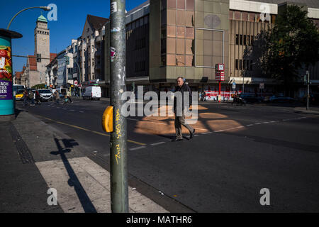 Un homme traverse la rue dans une flaque de lumière dorée à Berlin, Allemagne. Banque D'Images