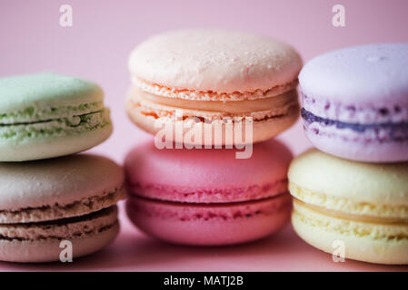 Gâteau sucré macarons français (ou macarons) avec des couleurs pastel vintage tone sur fond rose. Banque D'Images