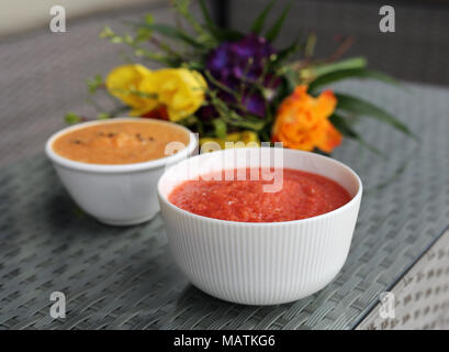 Bricolage maison deux smoothies (berry Smoothie orange et violet) sur un balcon table avec des fleurs colorées en arrière-plan. Sain et Délicieux ! Banque D'Images