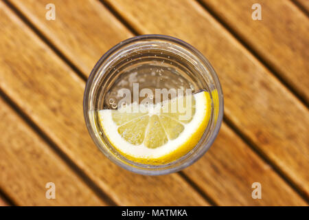 Eau gazeuse soda au citron en verre avec des bulles sur une table en bois brun Banque D'Images