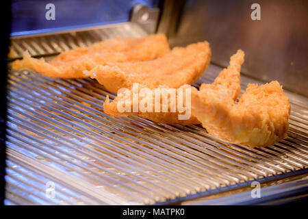 Poisson battu qui garde au chaud dans une étagère d'exposition d'un magasin de poissons et de copeaux, Hastings, East Sussex. Banque D'Images