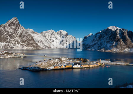 Vue aérienne sur Sakrisoya village avec rorbuer, montagnes enneigées et fjord. La saison d'hiver dans les Lofoten, Norvège Banque D'Images