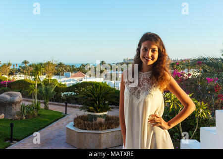 Femme debout dans le parc. Belle jeune femme souriant sur fond de palmiers et de la mer. Banque D'Images