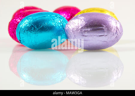 Des oeufs en chocolat pour Pâques aluminium coloré jour isolé sur fond blanc avec reflet, couleur coloré des œufs en chocolat pour Pâques. Banque D'Images