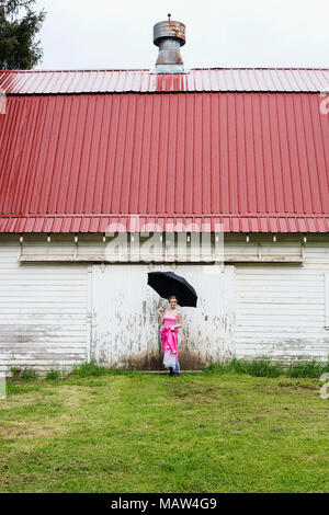 Une fille dans une robe rose, debout sous la pluie. Banque D'Images