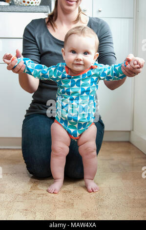 Un Bebe De 6 Mois L Aide Pour Se Lever De Sa Mere Photo Stock Alamy