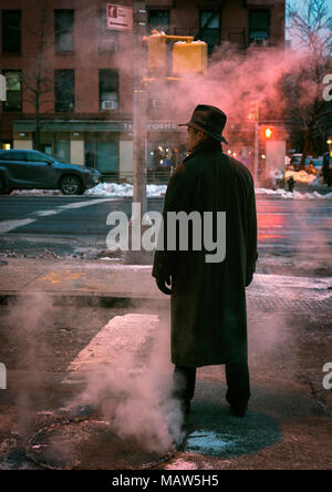 Un homme portant un fedora steamy debout sur une rue, dans la ville de New York. Banque D'Images