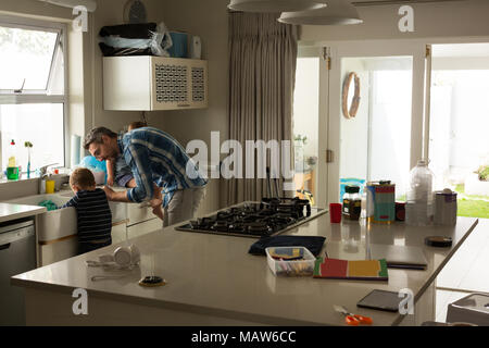 Père et fils dans la cuisine évier de nettoyage Banque D'Images