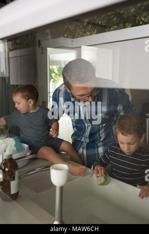 Père et fils dans la cuisine évier de nettoyage Banque D'Images