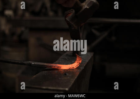 Blacksmith hammering une tige de métal chaud Banque D'Images