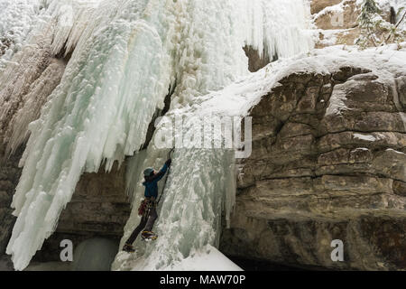 Male rock climber climbing ice mountain Banque D'Images