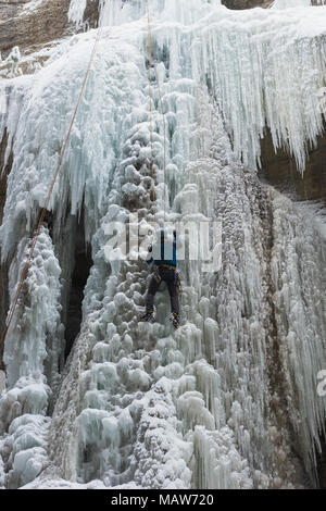 Male rock climber climbing ice mountain Banque D'Images