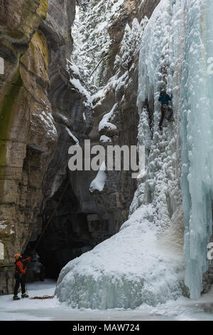 Male rock climber climbing ice mountain Banque D'Images