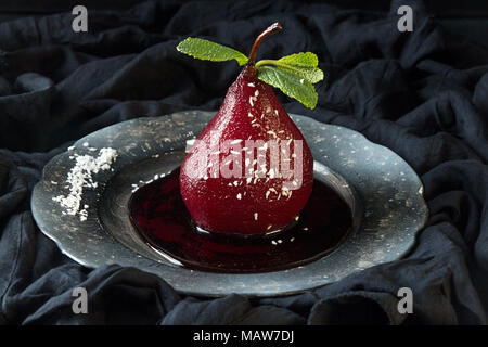 Les Poires au vin. Compote de poires dessert traditionnel au vin rouge sur fond de tissu noir. Banque D'Images