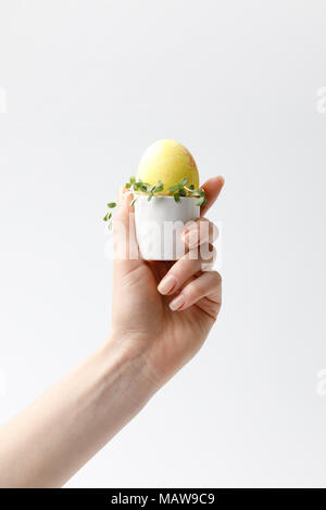 Portrait of woman holding peint jaune oeuf oeuf de Pâques dans stand isolated on white Banque D'Images