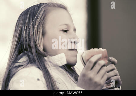 Happy teen girl eating a burger Banque D'Images