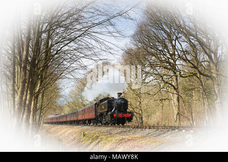 Train à vapeur britannique d'époque à l'ancienne, qui se délecte dans la campagne boisée sous le soleil du printemps. Banque D'Images