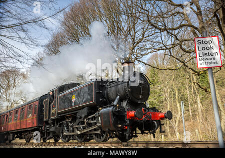 SVR locomotive à vapeur no.1501 soufflant le long à travers la campagne du Worcestershire dans le soleil de printemps. Arrêter de regarder écouter, méfiez-vous des trains signe. Banque D'Images