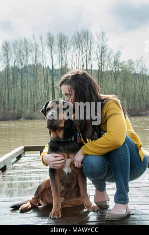 Une femme et son chien assis près d'une rivière. Banque D'Images