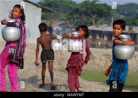 Khulna, Bangladesh - Octobre 08, 2014 : enfants bangladais transporter l'eau potable après les recueillir à partir d'une source d'eau douce dans la zone côtière à Khulna, Banque D'Images