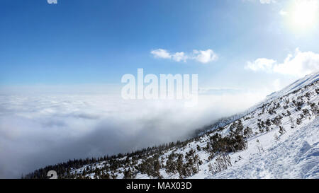 Vue depuis la montagne couverte de neige en hiver à inversion de température formant mer de nuages vus du dessus. Banque D'Images