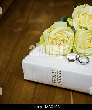 Close up d'argent mariage blanc sur la Sainte Bible avec bouquet de rose en bois rustique sur Banque D'Images