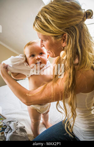 Une mère s'habiller son nourrisson de 10 mois. Banque D'Images