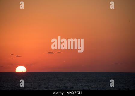 Orange-feu coucher de soleil sur un océan tropical calme comme l'orbe du soleil sous l'horizon avec vignette côté Banque D'Images