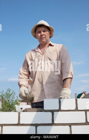 Maçon construit un mur de briques blanches Banque D'Images