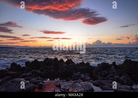 Cefalù, Italie, Sicile le 16 août 2015. Le coucher de soleil vu depuis le port de Cefalù. Ciel en feu et lave-réflexions colorées au milieu des rochers . Banque D'Images